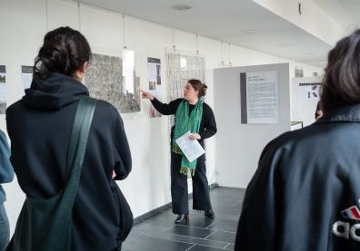 Dans une galerie d'exposition une femme raconte une oeuvre aux visiteurs