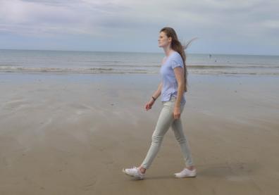 Une jeune femme marche sur la plage. Image extraite du film “Et la vie va…”