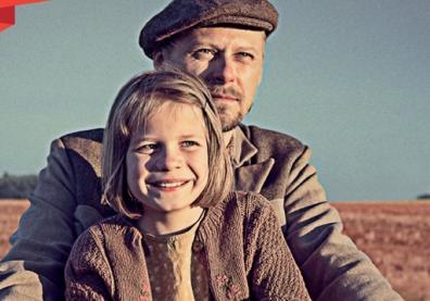 un portrait d'un homme qui porte un béret et d'une petite fille blonde devant lui sourit. On imagine que l'homme conduit un vélo avec la petite fille à l'avant.