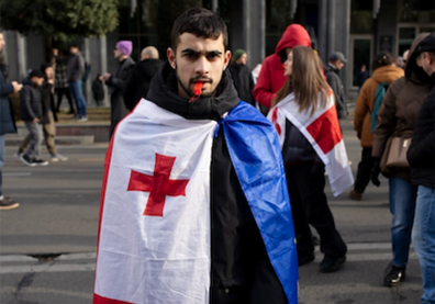 Portrait d'un jeune homme barbu avec une cape faite avec deux drapeaux