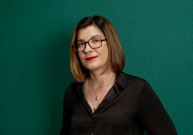 Photo d'une femme sur fond vert avec des cheveux châtains et des lunettes