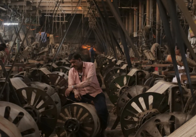 Un homme au milieu d'une usine de tissage