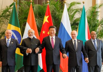 Les chefs d'états des BRICS devant leurs drapeaux se tiennent les mains 