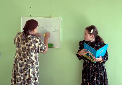 Une femme écrit sur un tableau en regardant l'autre qui tient un cahier 