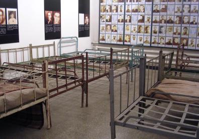 une pièce avec des lits en fer et des photos aux murs