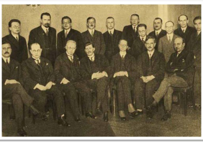 Photo en noir et blanc d'hommes en costumes noires assis et debout