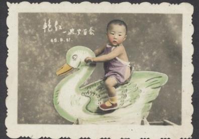Enfant à cheval sur un cygne à bascule