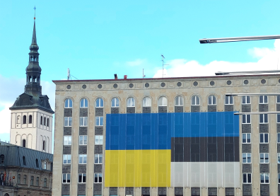Un immeuble avec deux drapeaux accrochés et sur la gauche un clocher