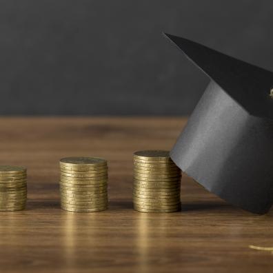 Toque universitaire et pièces de monnaie empilées sur une table
