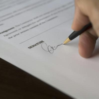 Main qui signe un document papier