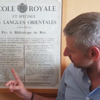 Christophe Pereira devant le texte de l'Ecole Royale et Spéciale des Langues Orientales Vivantes affiché dans les anciens salons de l'INALCO à la Rue de Lille