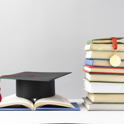 Front view of stacked books, a graduation cap and an open book for education day