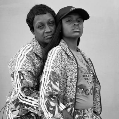 Portrait de deux femmes, la maman prend dans ses bras sa fille de dos