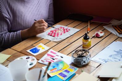 Une personne colorise un dessin représentant une part de gâteau à l'aide d'un pinceau et d'encre colorée