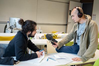 Un étudiant tend un micro vers un camarade pour l'interviewer