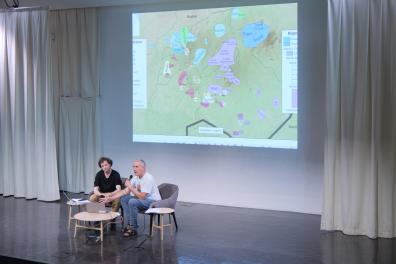 Two men sit and give a presentation in the auditorium