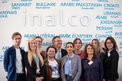 Photo de groupe des participants et participantes du premier workshop LANG-PACT, posant devant la fresque des langues de l'Inalco