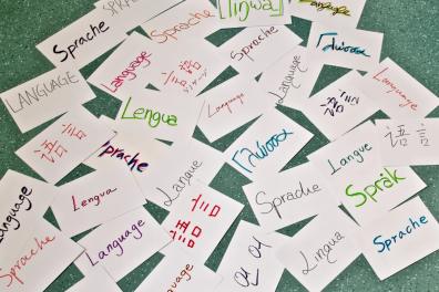 Un tas de feuilles de papier au sol, sur lesquelles sont écrites "Langue" dans plusieurs langues différentes