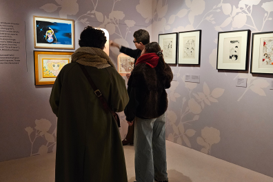 Un étudiant parle devant des planches de mangas à un public au coin d'une salle du musée
