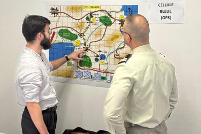 Un étudiant et un homme en uniforme se tiennent debout devant une carte