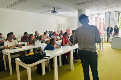 Un homme de dos se tient devant une classe 