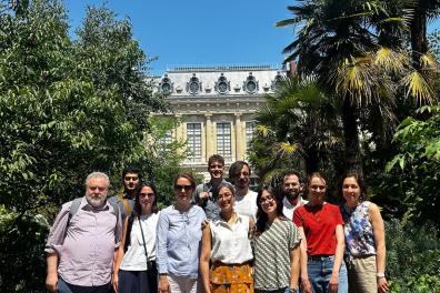 Un groupe de personnes prennent une photos devant un bâtiment entouré l'arbres 