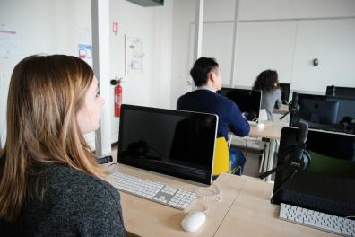 Trois étudiants sont devant des ordinateurs durant un cours