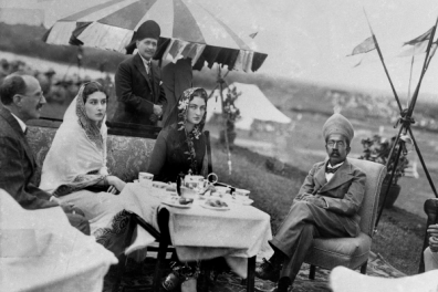 deux femmes et trois hommes assit autour d'une table en pleine air.