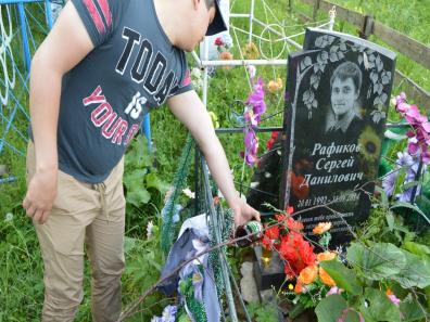 Jeune homme se recueille sur une tombe fleurie