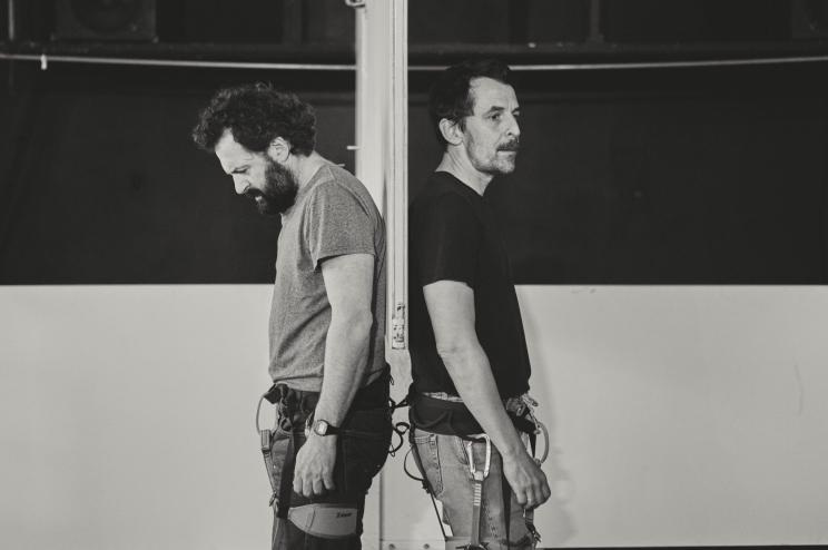 Deux hommes de dos accrochés par un harnais 