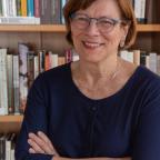 Portrait d'une femme souriante devant une bibliothèque 
