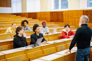 Un groupe d'étudiants dans un amphithéâtre écoutent avec attention un enseignant qui donne cours