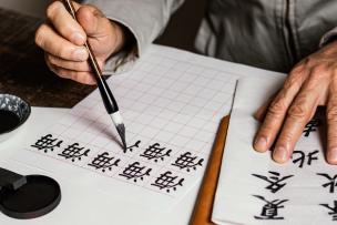 Une personne écrit des symboles chinois sur du papier blanc