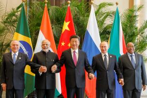 Les chefs d'états des BRICS devant leurs drapeaux se tiennent les mains 