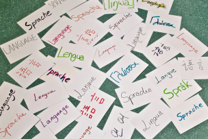 Un tas de feuilles de papier au sol, sur lesquelles sont écrites "Langue" dans plusieurs langues différentes