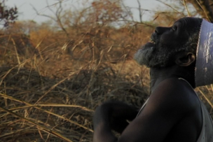 Un homme de profil regarde vers le ciel. Il se trouve dans la nature