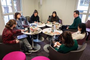 Plusieurs étudiants sont assis devant des tables recouvertes de mangas