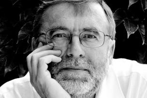 Portrait d'un homme avec des lunettes, le menton posé sur sa main il regarde l"objectif