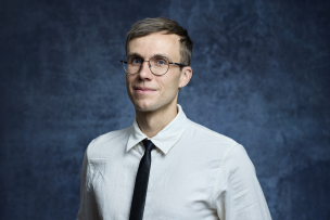 Photo sur fond bleu d'homme à lunettes avec une chemise blanche et cravate noire