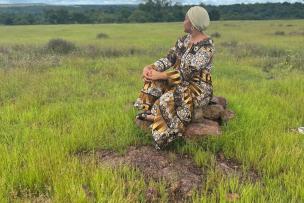 Une femme, isolée dans un espace indéfini et tournée vers un horizon certes dégagé mais surplombé par des nuages épais