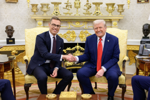 Photo de deux hommes en costume bleu qui se serrent la main devant une cheminée dorée