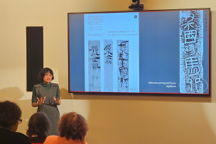 Une enseignante parle dans un auditorium avec un écran derrière pour illustrer 