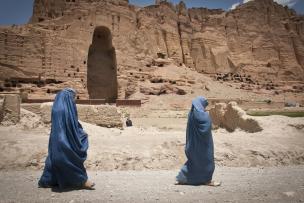 Two women walk past the huge cavity where one of the ancient Buddhas of Bamiyan, known to locals as the "Father Buddha," used to stand, June 17, 2012.