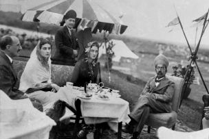 deux femmes et trois hommes assit autour d'une table en pleine air.